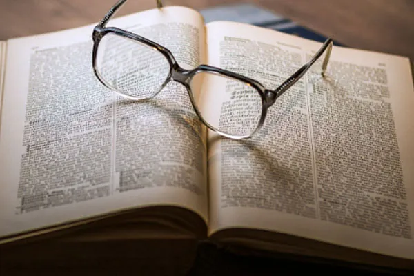 Briller der ligger på en åben bog. 