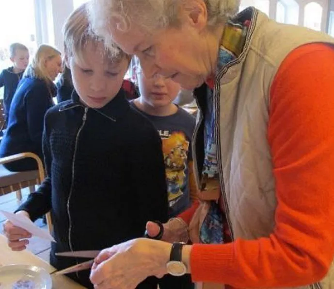 Minikonfirmandunderviser Gerda hjælper en minikonfirmand med at klippe.